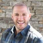 Smiling man in front of stone wall