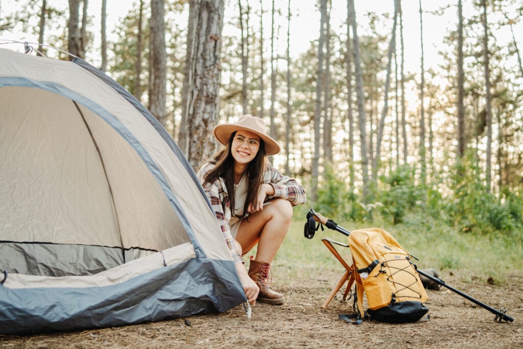 Woman setting up tent in forest campsite