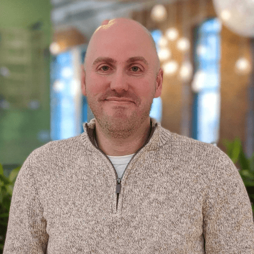 Smiling man in a light sweater indoors