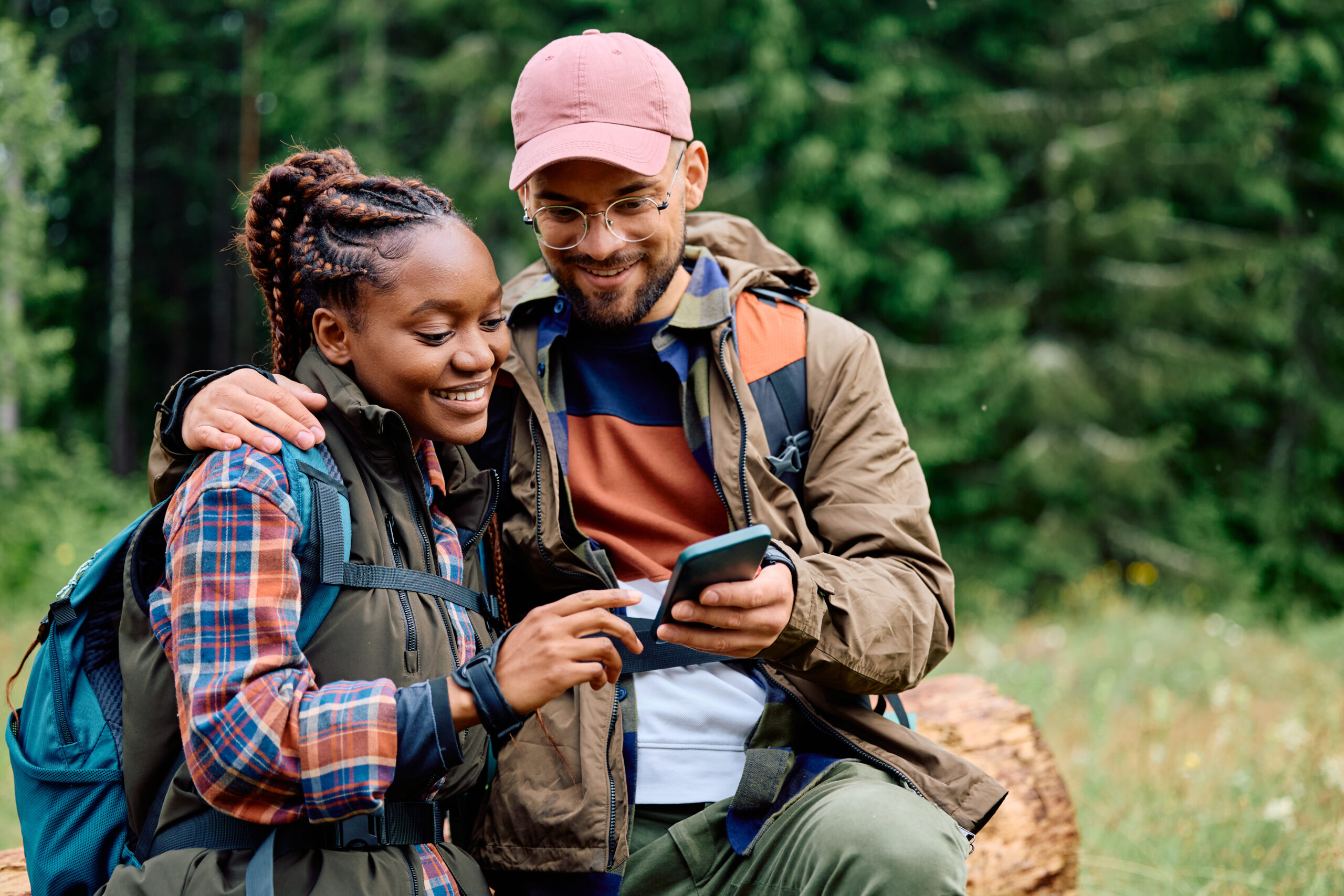 Hikers checking phone in forest setting.