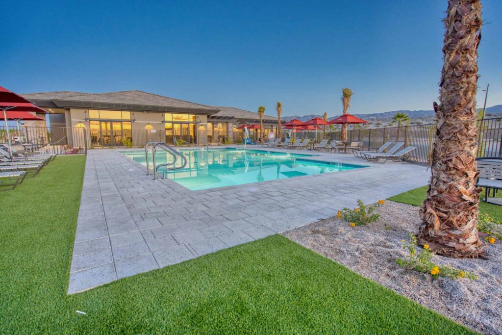 Outdoor swimming pool at sunset with lounge chairs.