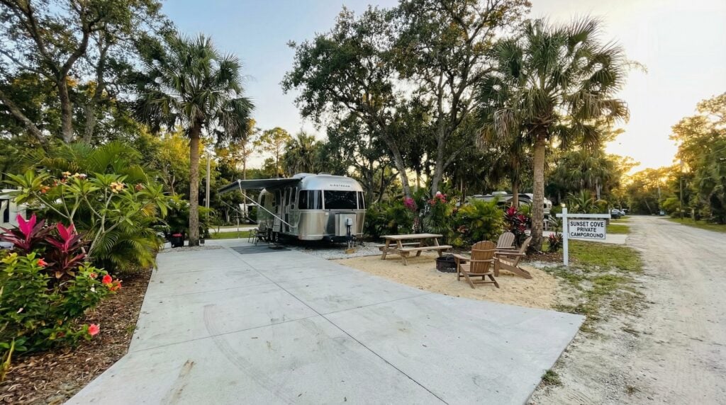 Airstream trailer at tropical campground during sunset.