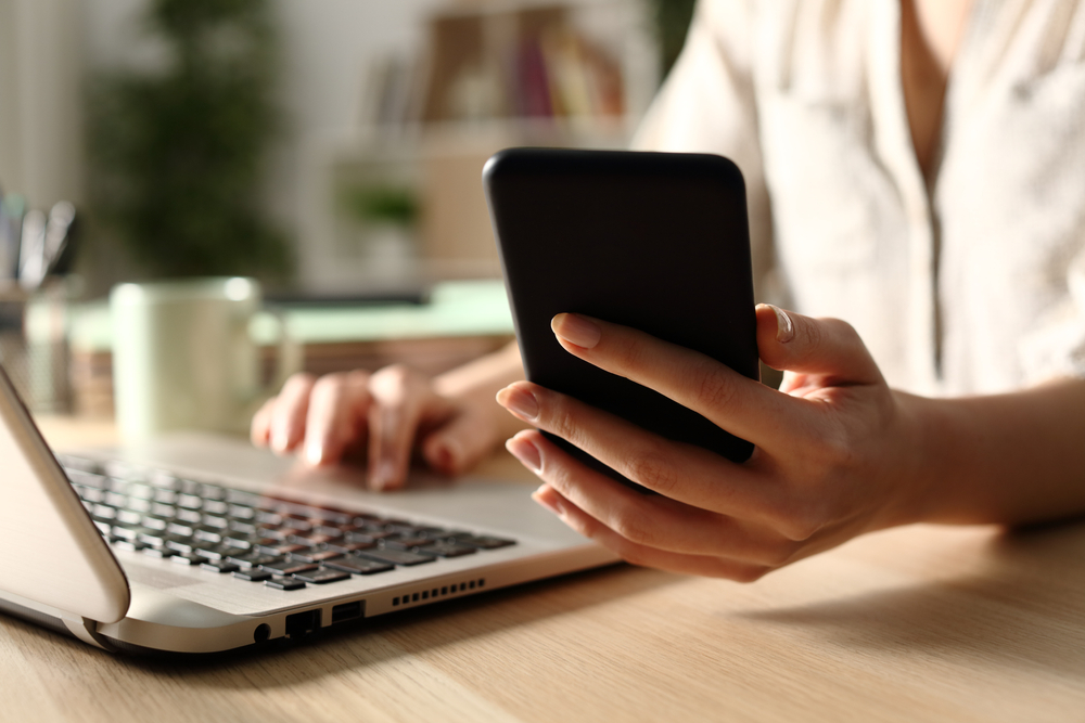 Person using laptop and smartphone simultaneously